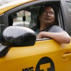 Serious taxi driver in glasses sitting in yellow automobile and looking up on street in city in daytime