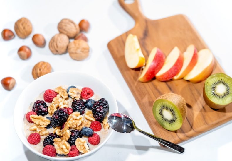 A nutritious breakfast bowl featuring fresh berries and walnuts, served with sliced fruit and kiwi.