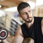A determined man lifting a dumbbell indoors, showcasing strength and fitness.
